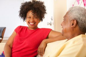 Two African Americans smiling at one another on a couch.