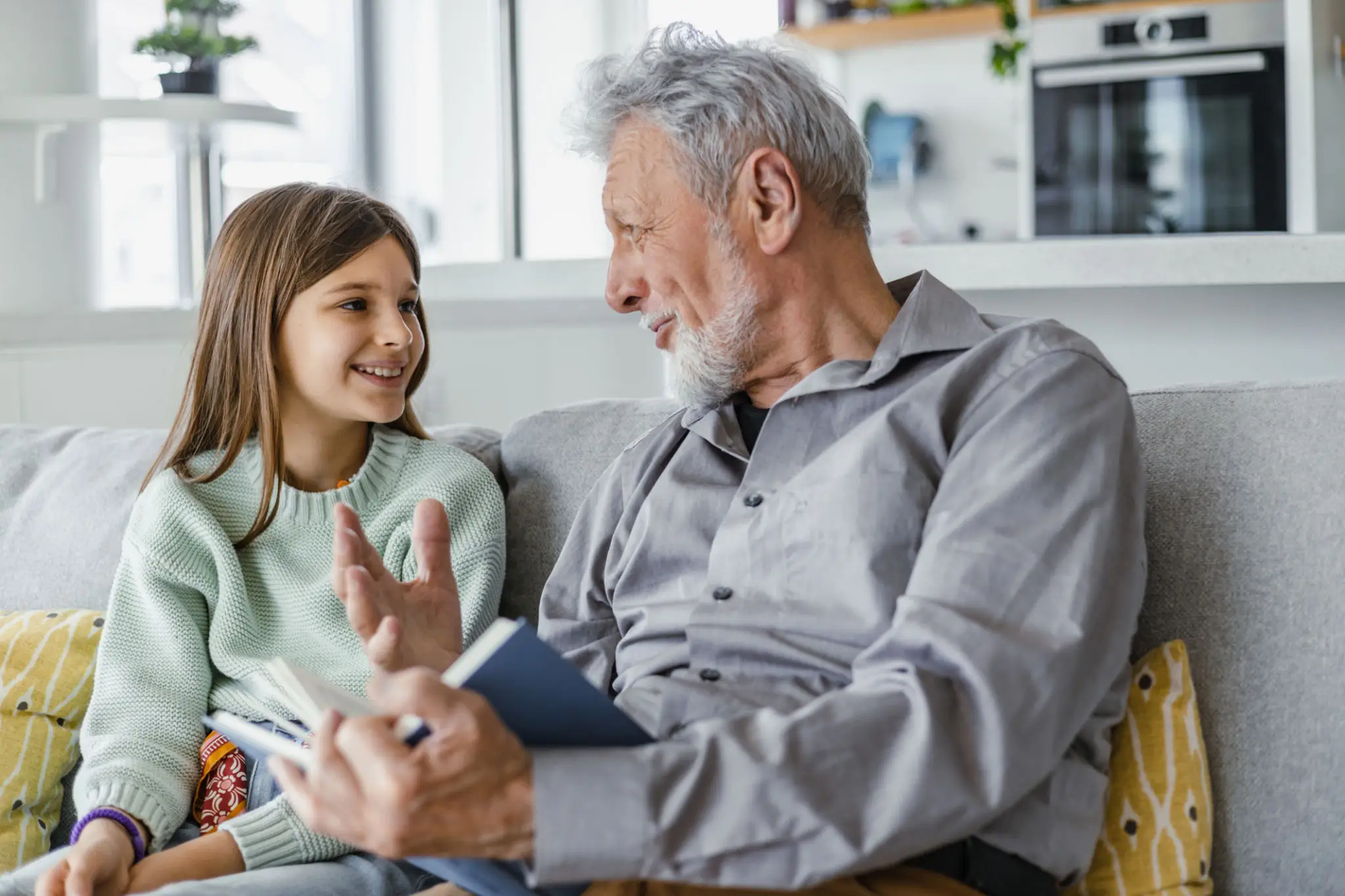 Grandfather and granddaughter talking on couch.