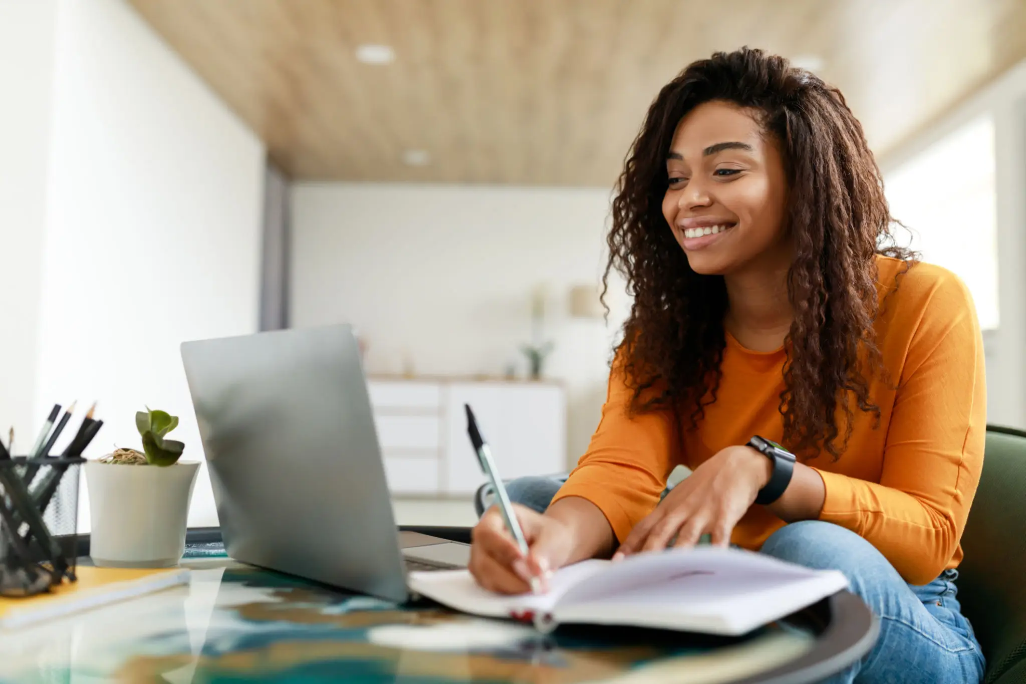Woman smiling while writing on notepad.