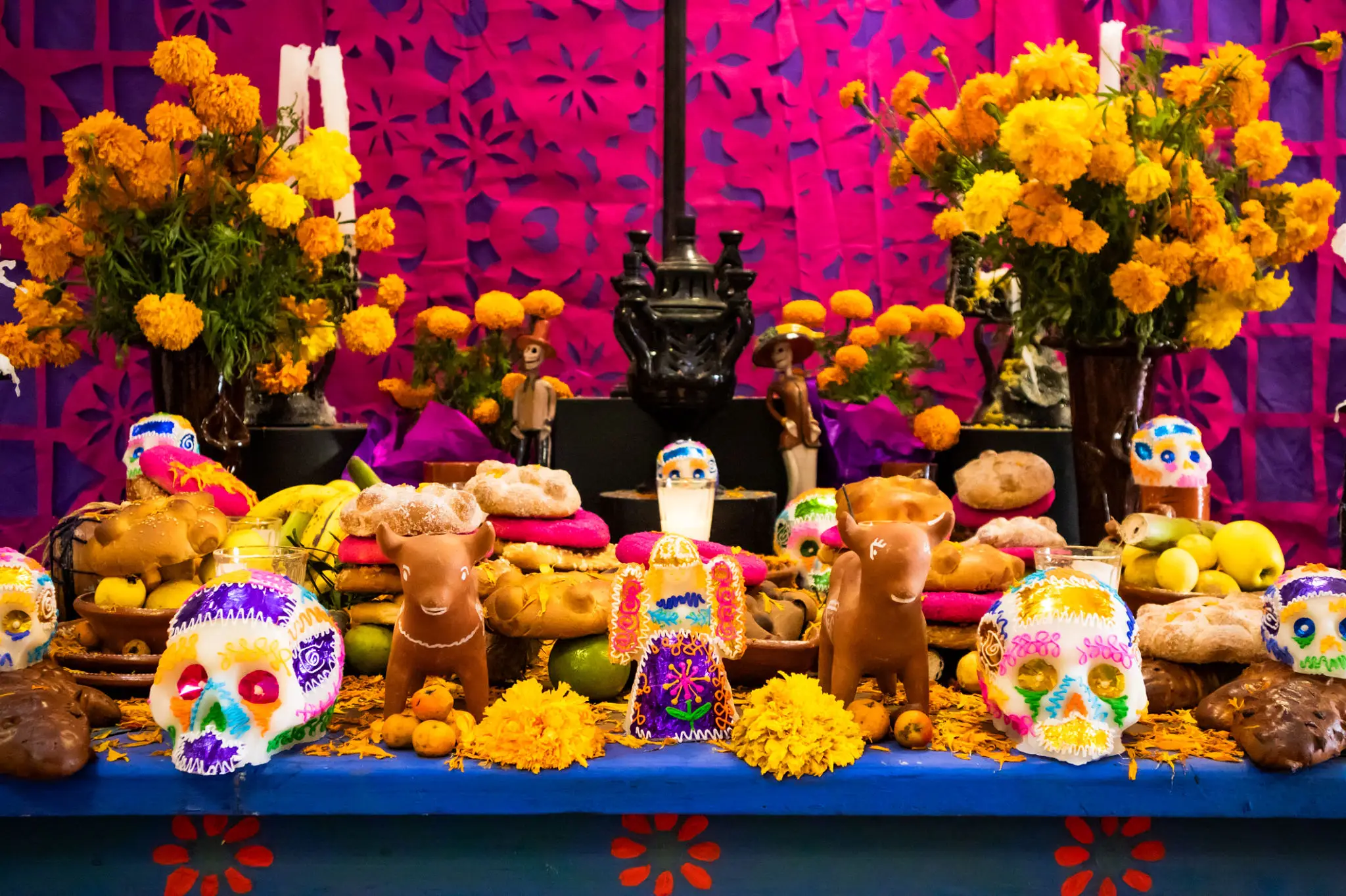 Colorful Day of the Dead altar with marigolds, skulls, and figurines.