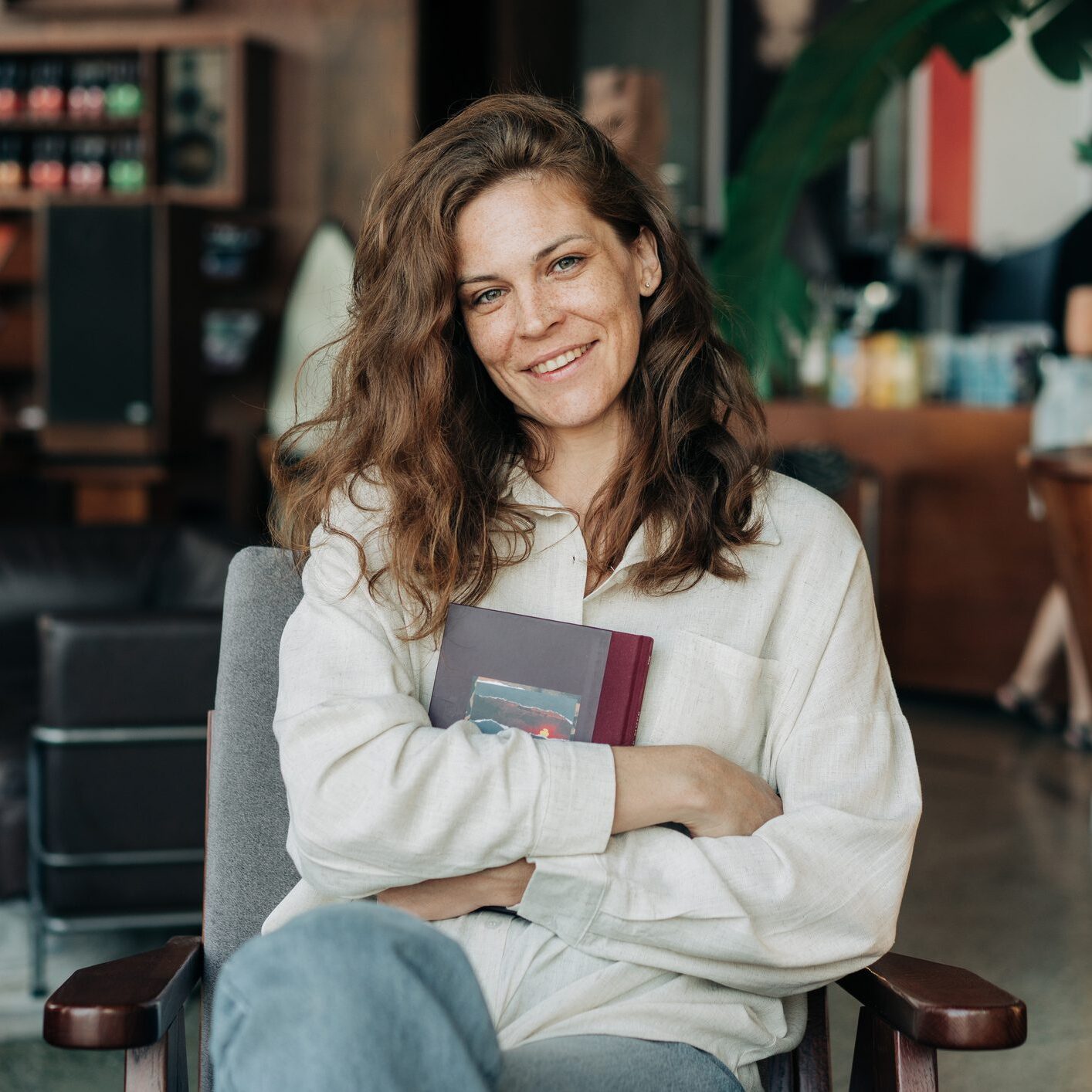 Portrait of smiling caucasian pretty redhead woman sitting in a cafe holding a notebook.